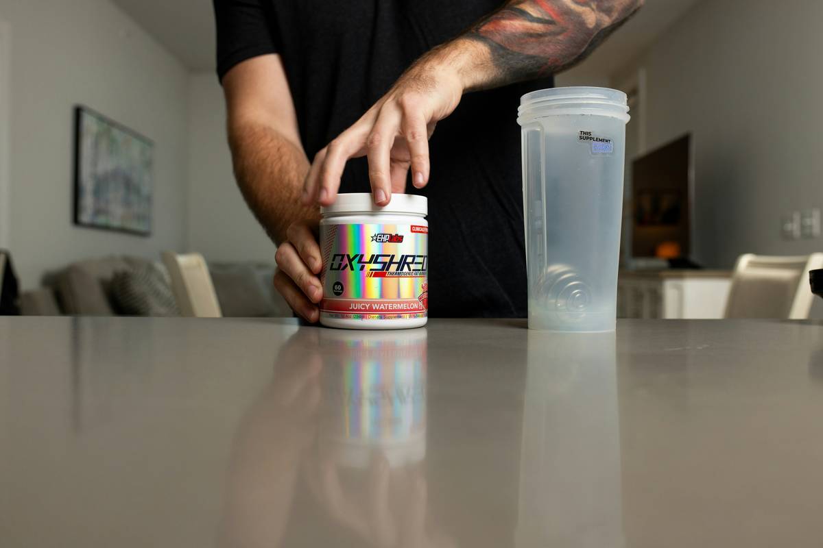 l carnitine for gym: bottle of L-carnitine supplement next to dumbbells and a shaker bottle