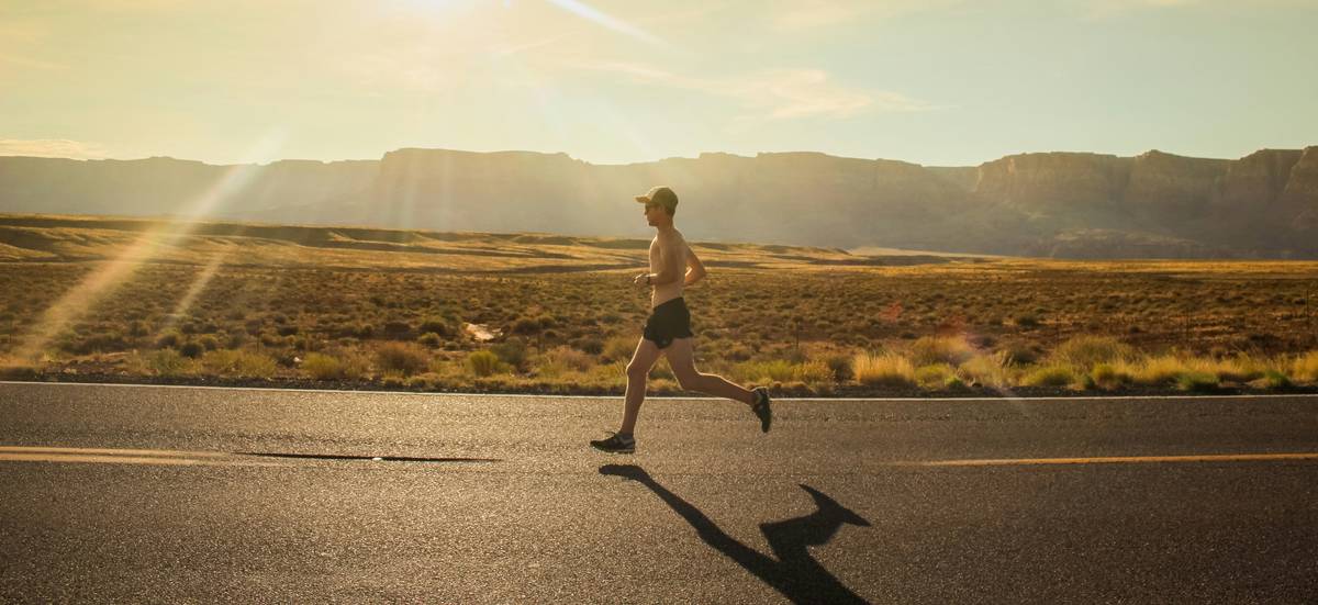 fat burner carnitine burning exercise at: woman jogging outdoors with supplement bottle in hand